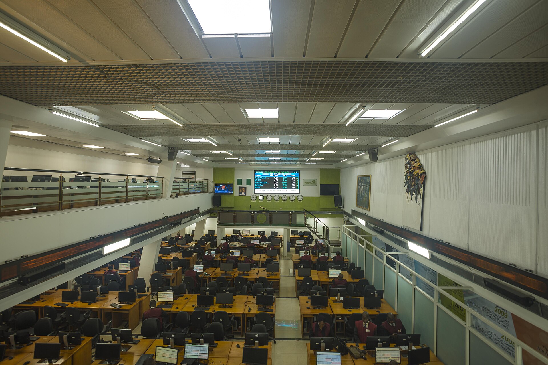 Sala de operaciones de una bolsa, con filas de puestos y pantallas